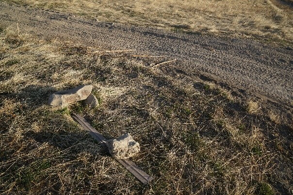 sign laying on the ground underneath a small rock